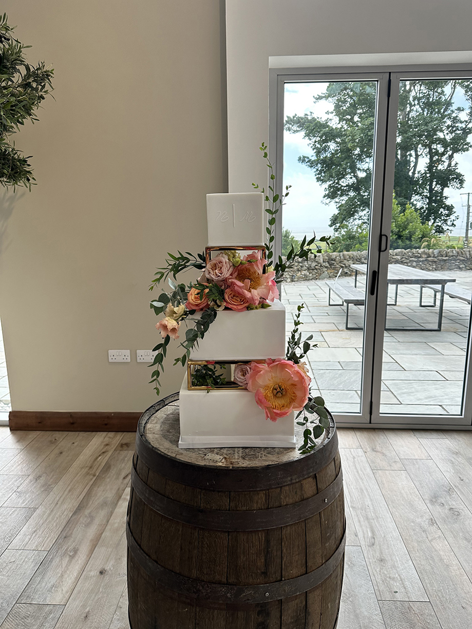 White three-tier square cake with orange flowers and leaves